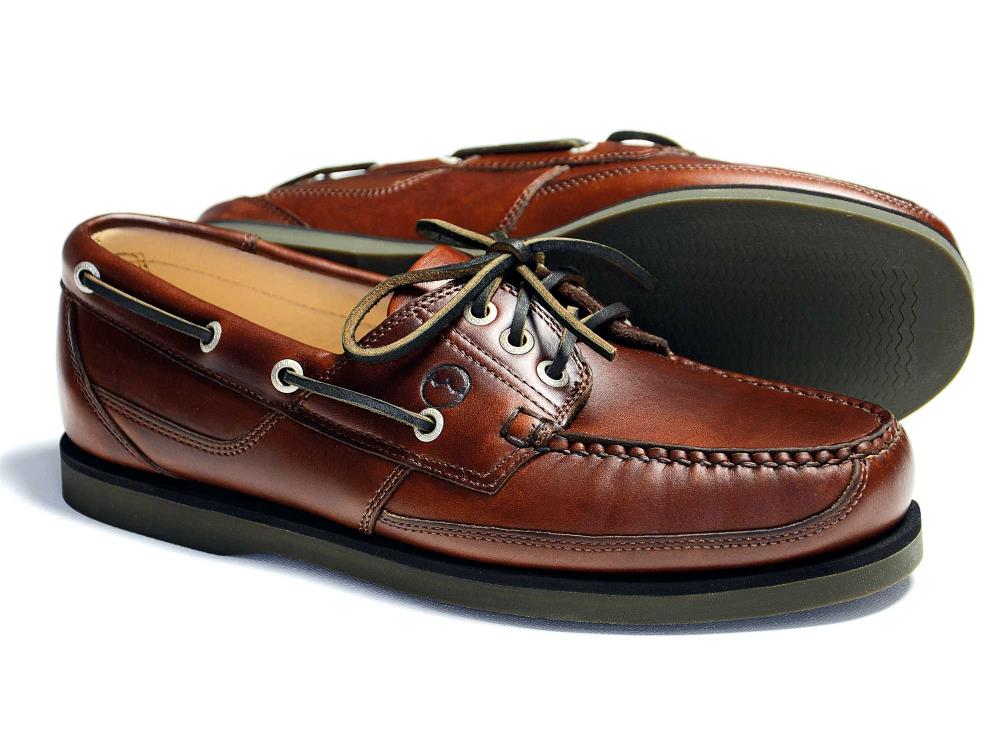 The Orca Bay CHEROKEE Elk Deck Shoe features brown leather, black laces, white stitching, and a non-slip rubber sole. One shoe stands upright while the other lies on its side to display the sole—ideal for boating or casual wear.