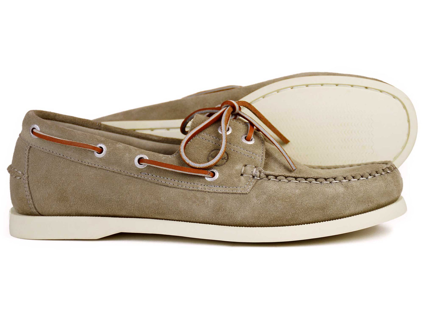 The MAINE Ladies Taupe Suede Boat Shoe with White Sole by Orca Bay features non-slip soles, white eyelets, and brown leather laces; one shoe lies flat, the other is on its side behind it.