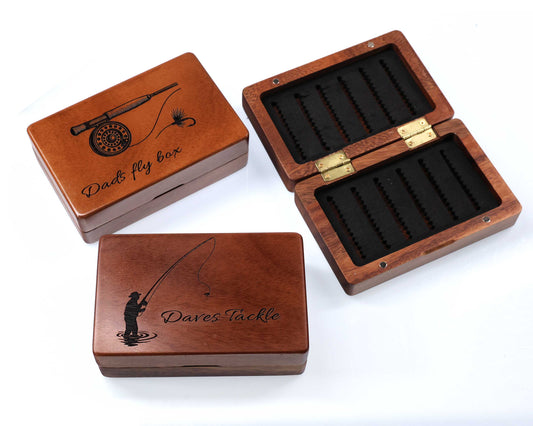 Three Cathcart Elliot Personalised Pocket Sized Walnut Fishing Fly Boxes—two engraved (“Dad’s fly box” with rod; “Dave’s Tackle” with fisherman); one open, showing slotted foam interior—a unique 14x9cm gift for anglers.