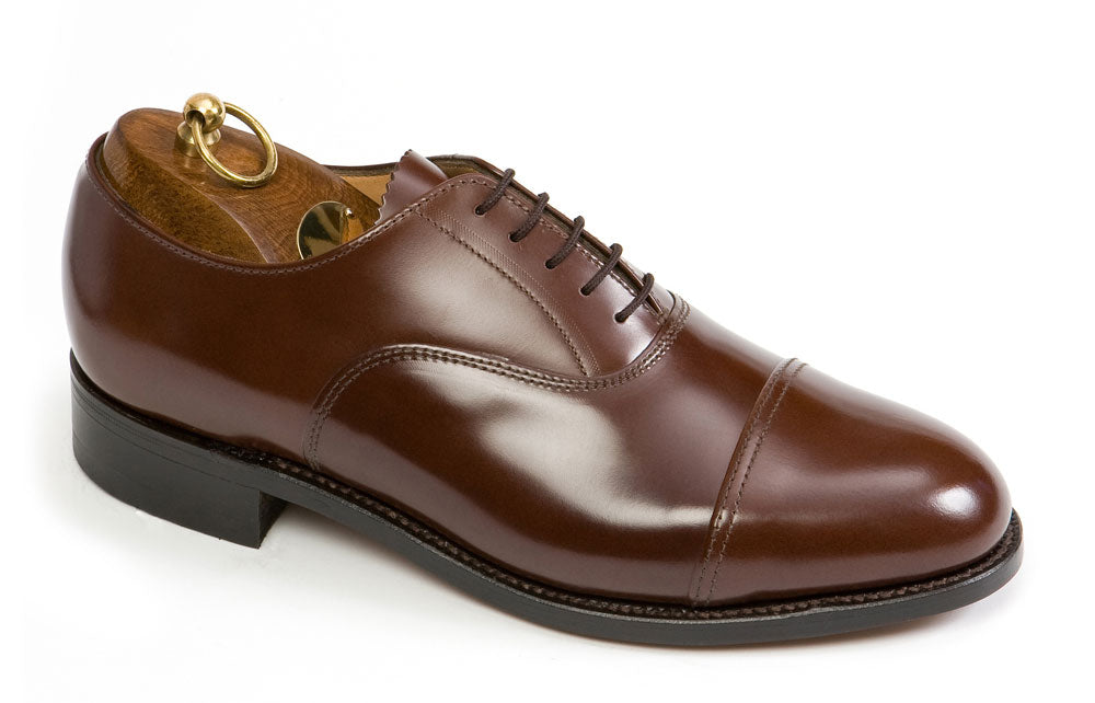 The OXFORD Wide F Fitting Officers Brown Oxford Shoes by Sanders feature polished brown leather, a cap toe, dark laces, and a wooden shoe tree with a brass handle—ideal for those seeking classic mens dress shoes from Sanders.