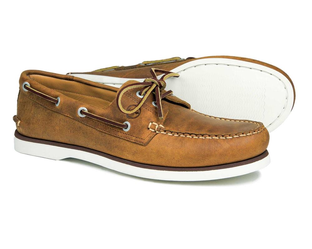 The PORTLAND Mens Orca Bay Deck Shoes in sand nubuck showcase classic moccasin-style stitching, tan laces, and white non-marking rubber soles. One shoe stands upright and the other lies on its side, revealing the soles underside.