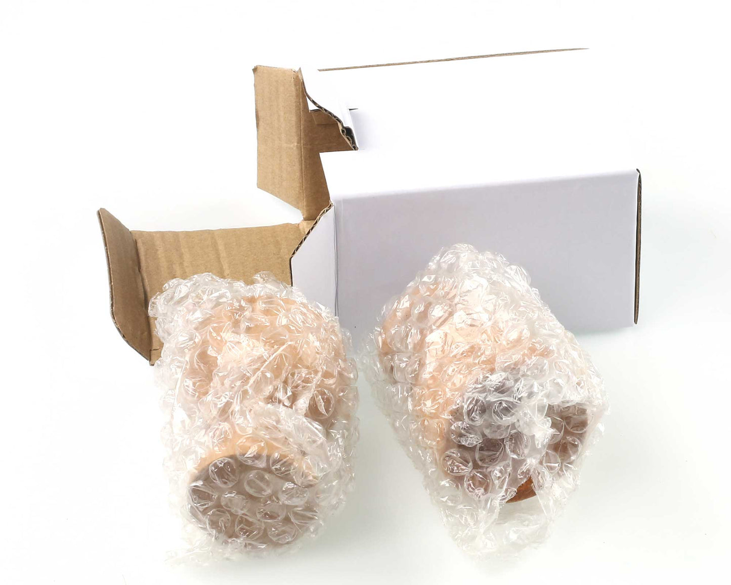 Two Cathcart Elliot personalised wooden egg cups (set of 2) are wrapped in bubble wrap and placed next to an open white cardboard box on a white surface.