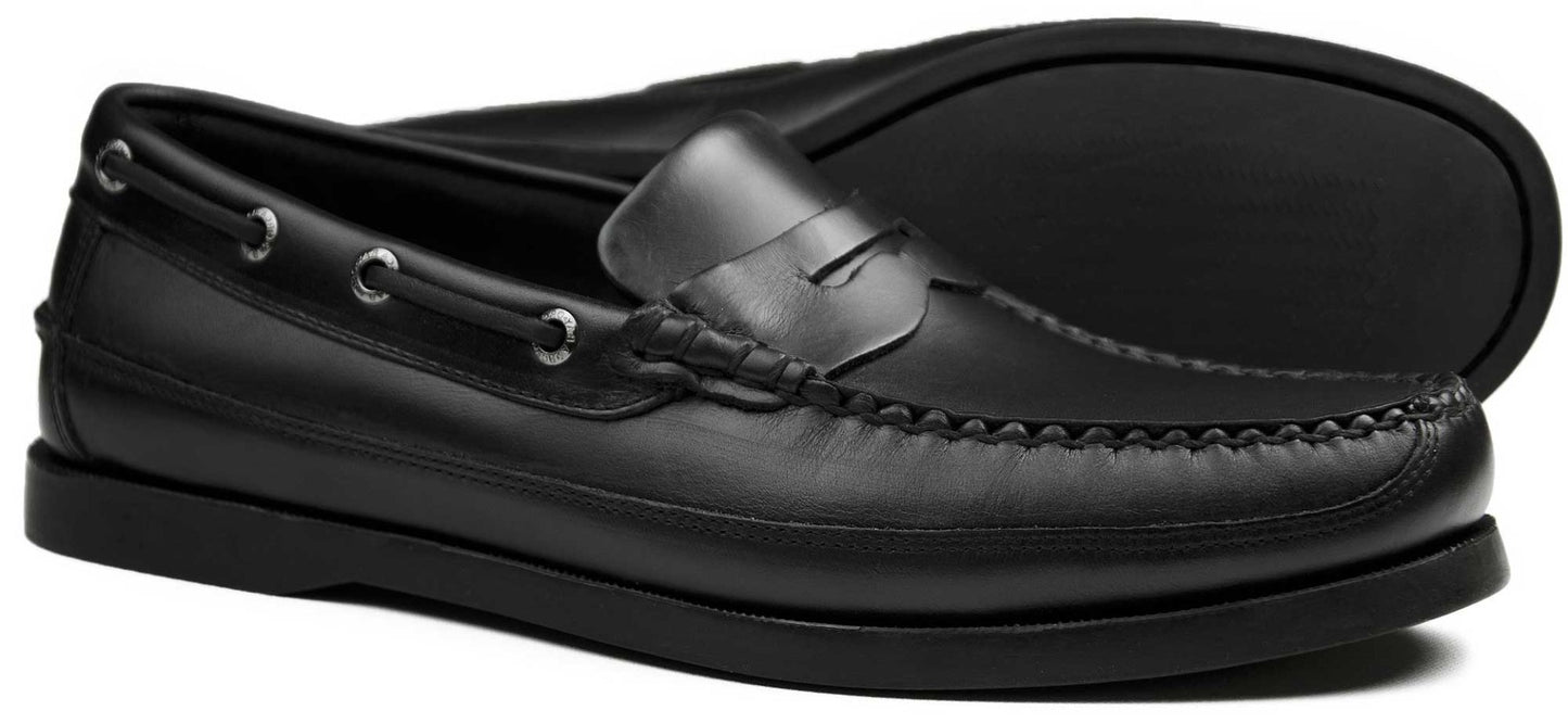 The FRIPP Black Leather Slip-on Loafer by Orca Bay is a sleek moccasin-style shoe featuring decorative metal eyelets, a classic penny strap, non-slip sole, low heel, and visible edge stitching.