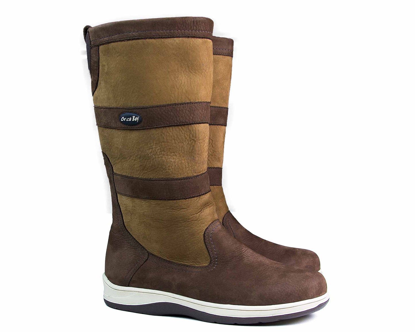 The STORM Unisex Waterproof Sailing Boot by Orca Bay is a brown nubuck boot with lighter brown uppers, dark brown accents, side tag, rounded toes, and non-slip white soles on a black base. Designed for professional sailors facing diverse conditions.