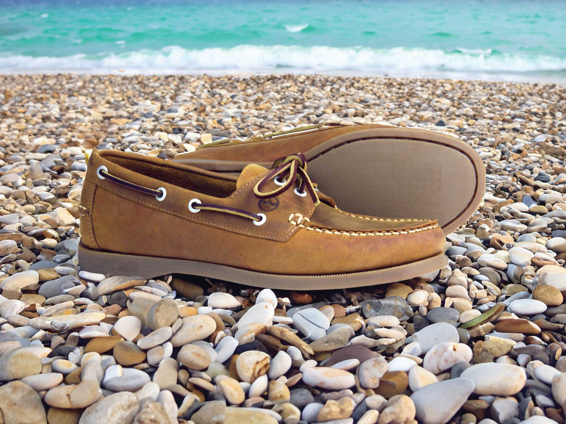 Orca Bay Creek Boat Shoe in Sand Nubuck on a pebble beach