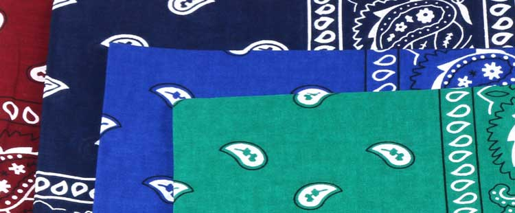 Three bandanas are layered: a red one at the back, a blue one in the middle, and a green one in front. Each bandana features a paisley pattern with white designs.