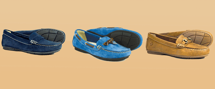 Three pairs of moccasins are displayed against a beige background. The shoes are navy blue, light blue, and brown, each featuring a rubber sole with distinct stitching and decorative details on the uppers.