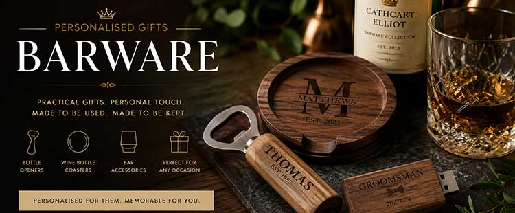 A display of personalized barware gifts including a wooden coaster, bottle opener, USB stick, whisky glass, and a bottle, all engraved with names and decorative monograms on a dark background.