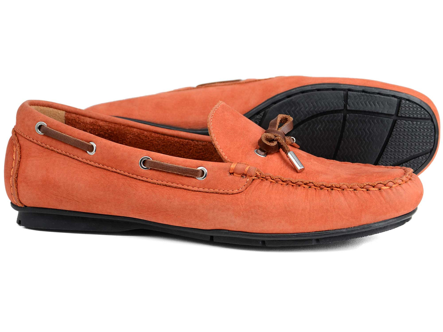 The Orca Bay Ballena Ladies Burnt Orange Loafers feature a moccasin design with brown laces and black rubber soles, shown with one shoe upright and the other on its side to display the sole.