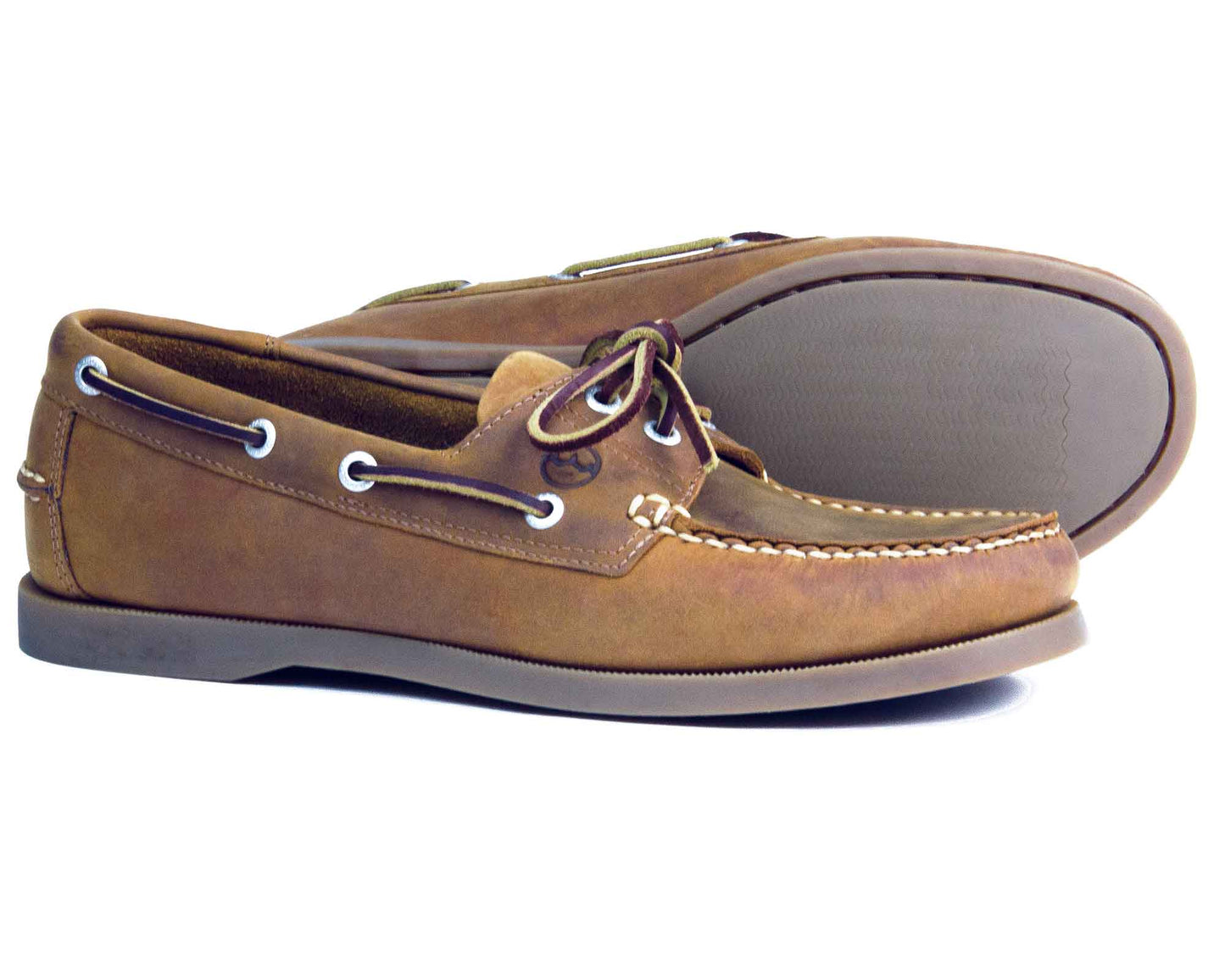 A pair of Orca Bay Men’s Creek Deck Shoes in sand nubuck leather with white stitching, rubber soles, and white eyelets—one shoe standing upright and the other lying on its side to showcase the sole. These classic Orca Bay boat shoes offer timeless style and practical comfort.