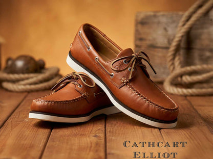 Orca Bay Mens Portland Deck Shoe in Havana Brown Leather with white soles is displayed on a wooden surface, thick rope behind. The text "Cathcart Elliot" appears in the bottom right corner.