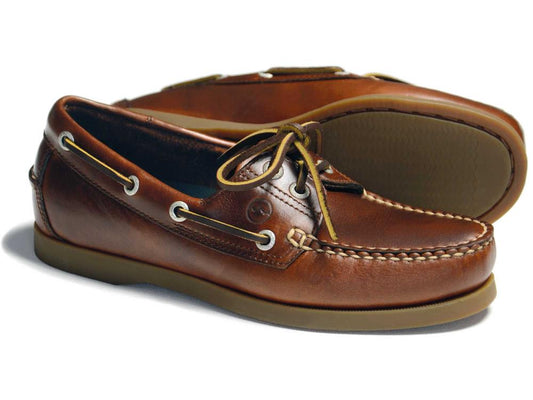 The CREEK Ladies Orca Bay Deck Shoe in Saddle Brown features salt-resistant leather, tan laces, white stitching, slip-resistant rubber soles, and visible side eyelets. This classic design has one shoe slightly in front of the other to showcase its sleek style. Brand: Orca Bay.