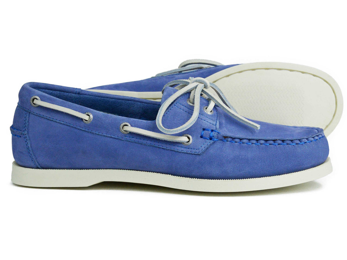 A pair of Orca Bay Ladies Sandusky Velvet Blue Deck Shoes, crafted in blue nubuck with moccasin-style construction, featuring white soles and white laces; one shoe stands upright while the other lies on its side to display the sole.