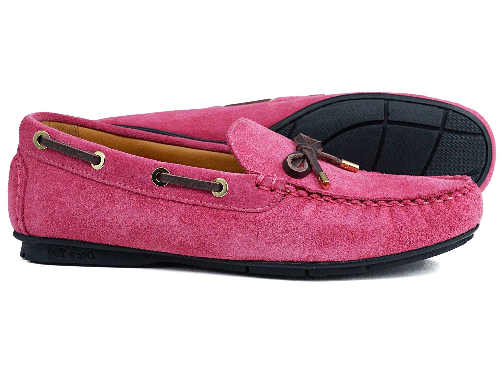 The VIENNA Ladies Sorbet Pink Suede Loafers by Orca Bay feature brown laces, gold-tone eyelets, and black non-slip rubber soles. One shoe stands upright while the other rests on its side to display the sole.