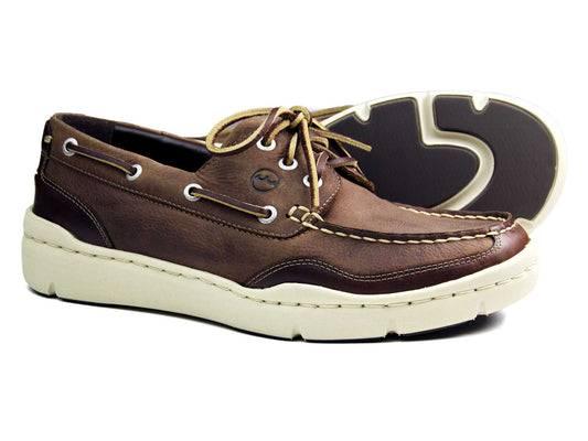 The ABERSOCH Mens Russet Brown Nubuck Deck Shoe by Orca Bay features white stitching, a siped rubber sole, lace-up detailing, and a rounded toe. One shoe is upright while the other is on its side, highlighting the soles design.