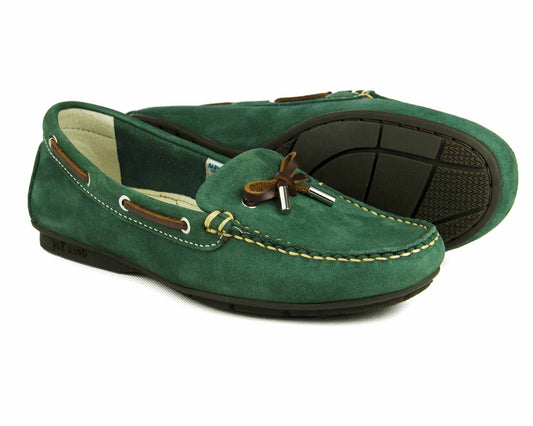 The BALLENA Ladies Green Loafer by Orca Bay features a moccasin style with brown laces, silver tips, white stitching, and non-slip rubber soles. One shoe stands upright while the other reveals its treaded sole.