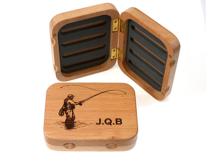 The Cathcart Elliot Personalised Beech Wood Fishing Fly Box Salmon / Trout Tackle Box is elegantly crafted from beech wood and features an engraved image of a fisherman along with the initials J.Q.B. When opened, the box reveals foam slots perfect for organising fishing flies, while a second closed box with matching engraving is displayed in front.