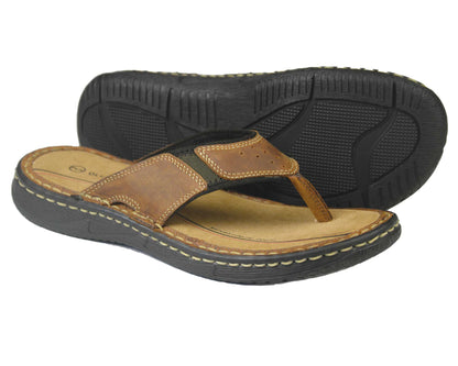 The BELIZE Mens Sandal by Orca Bay features sand nubuck leather flip flops with black rubber soles, tan cushioned footbeds, and visible stitching. One sandal is displayed upright; the other shows its sole.