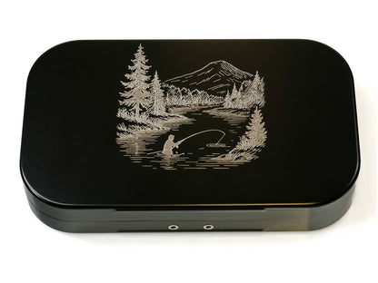 The Cathcart Elliot Personalised Black Aluminium Fly Box for Dry & Wet Flies makes an ideal engraved fishing gift for any angler, featuring a silver etching of a person fishing by a river with trees and mountains.