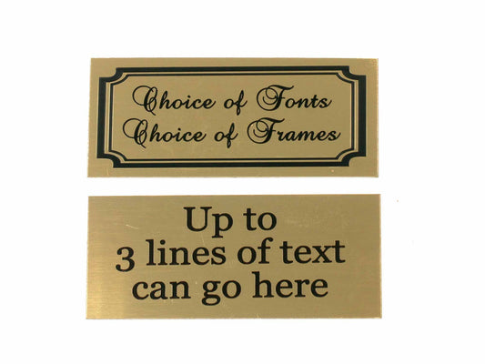 The image displays two Brass Effect Aluminium Plaques from Cathcart Elliot. The top plaque states Choice of Fonts Choice of Frames with a decorative border, while the bottom plaque reads Up to 3 lines of text can go here. These self-adhesive plaques offer free personalized text engraving.