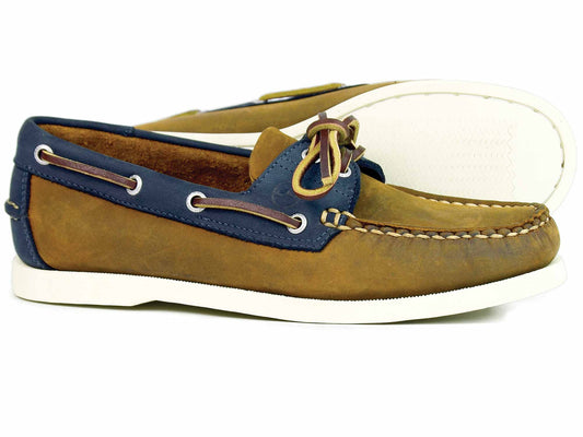 The CLOVELLY Ladies Sand Navy Nubuck Deck Shoe by Orca Bay is a pair of brown and navy leather boat shoes with moccasin construction, white soles, decorative side lacing, and a knotted lace on top, highlighting casual style and comfort.