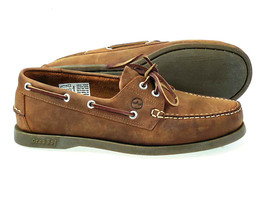 Introducing the Men’s Orca Bay Creek Deck Shoe – Boat Shoe Sand Nubuck by Orca Bay, expertly crafted from sand oiled nubuck leather. This pair features white stitching, lace detailing, and durable rubber soles. Displayed with one shoe upright and the other on its side to reveal the sole, these classic deck shoes from Orca Bay combine timeless style with lasting comfort.