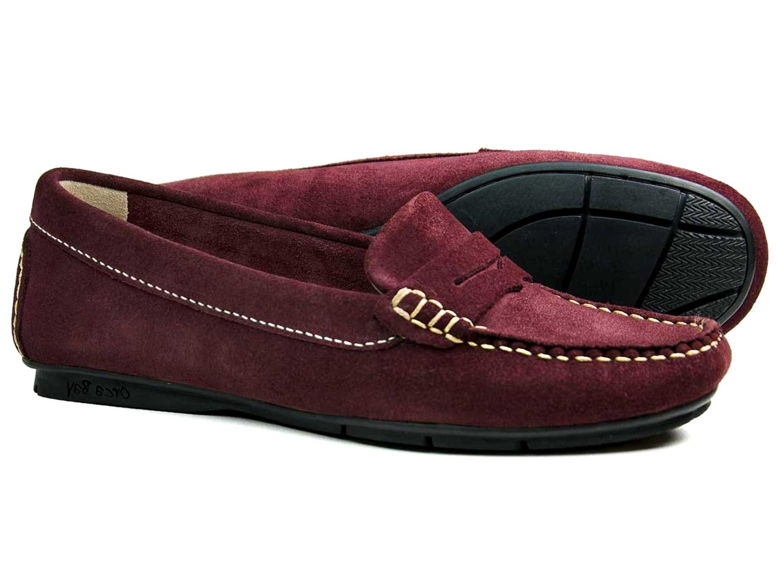 The FLORENCE WOMENS Burgundy Suede Loafer by Orca Bay features comfortable moccasin soles, a classic design with a decorative strap, and durable quality suede uppers. One loafer is displayed flat, and the other upright.