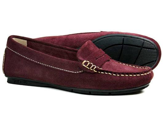 The FLORENCE WOMENS Burgundy Suede Loafer by Orca Bay features comfortable moccasin soles, a classic design with a decorative strap, and durable quality suede uppers. One loafer is displayed flat, and the other upright.