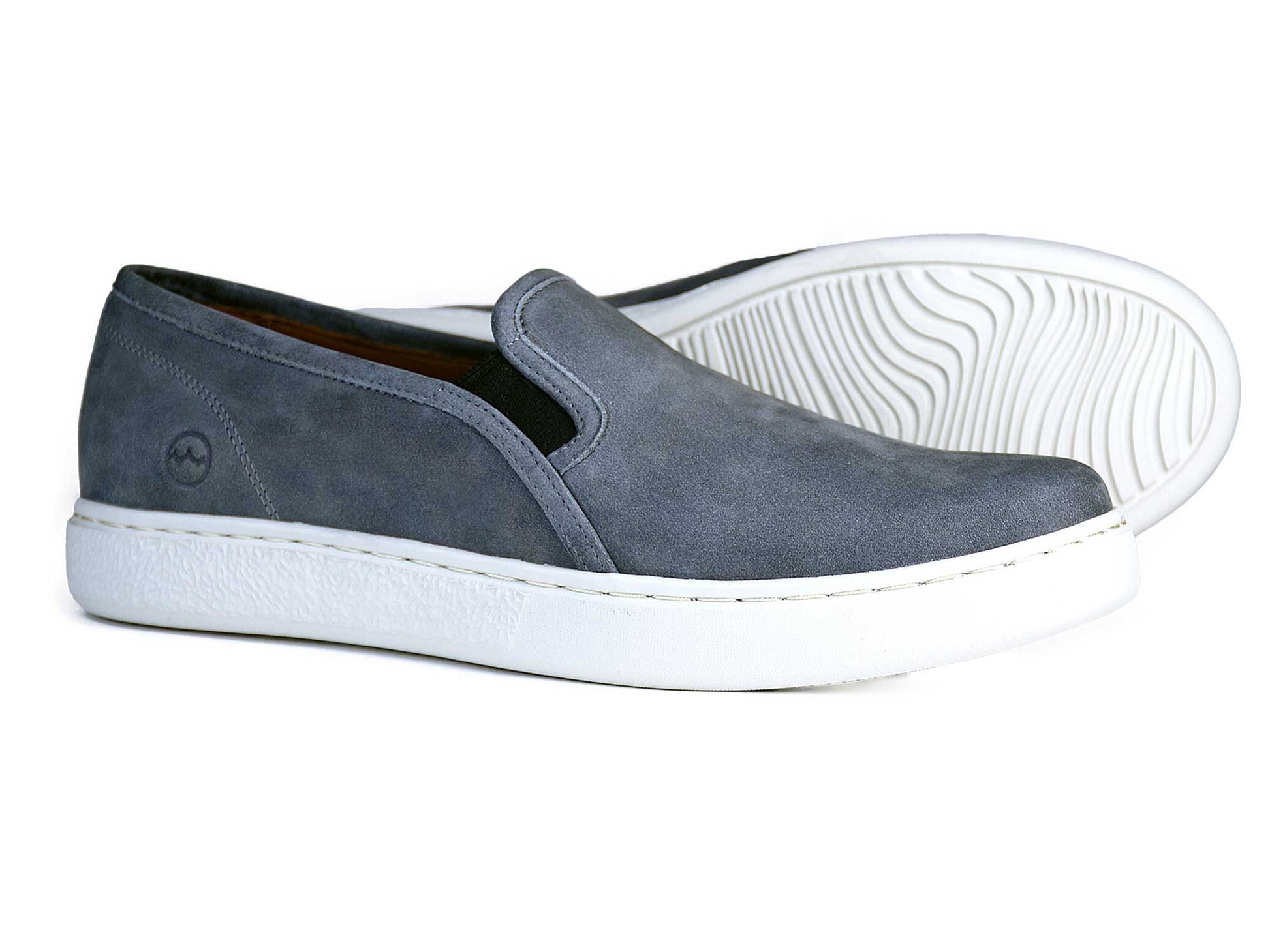 The FULHAM Mens Grey Loafers by Orca Bay are sleek slip-ons with a white shock-absorbing sole, a subtle side logo, and a textured wavy pattern underneath.