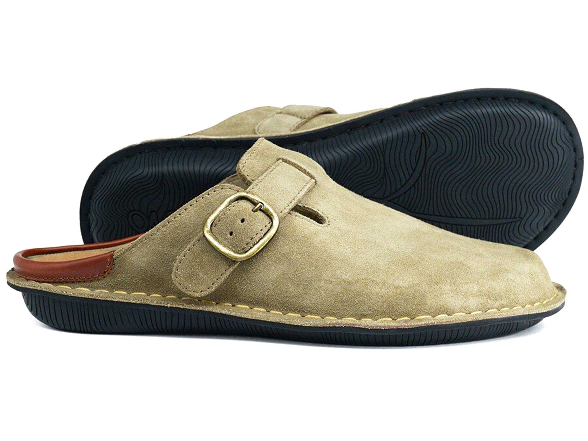The Orca Bay Garda Taupe Suede Clog Mule features an adjustable strap, black textured rubber soles, and tan stitching. One unisex mule from the Orca Bay brand stands upright while the other lies on its side in the background.