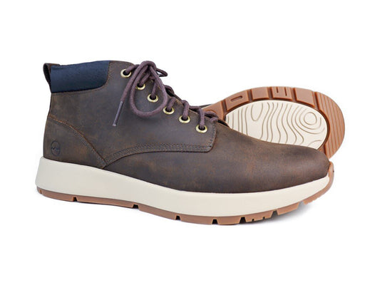 The KIELDER Mens Dark Brown Waterproof Boot by Orca Bay showcases its brown oiled nubuck leather with white soles and rugged tan outsoles. One boot stands upright while the other is tilted to display its sole design and textured grip.