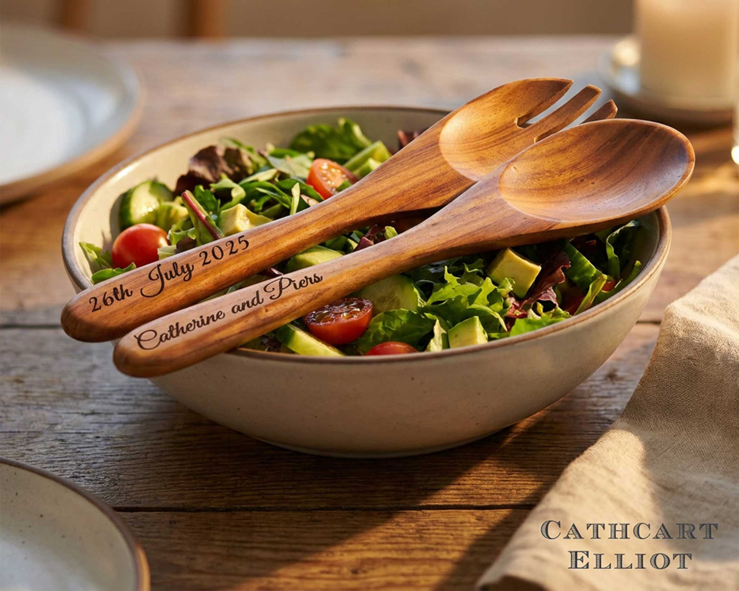 A salad bowl with greens, tomatoes, and cucumbers, served with Cathcart Elliot's Personalised Set of 2 Acacia Wood Salad Spoon and Fork Servers (25cm), engraved with "26th July 2025" and "Catherine and Piers".