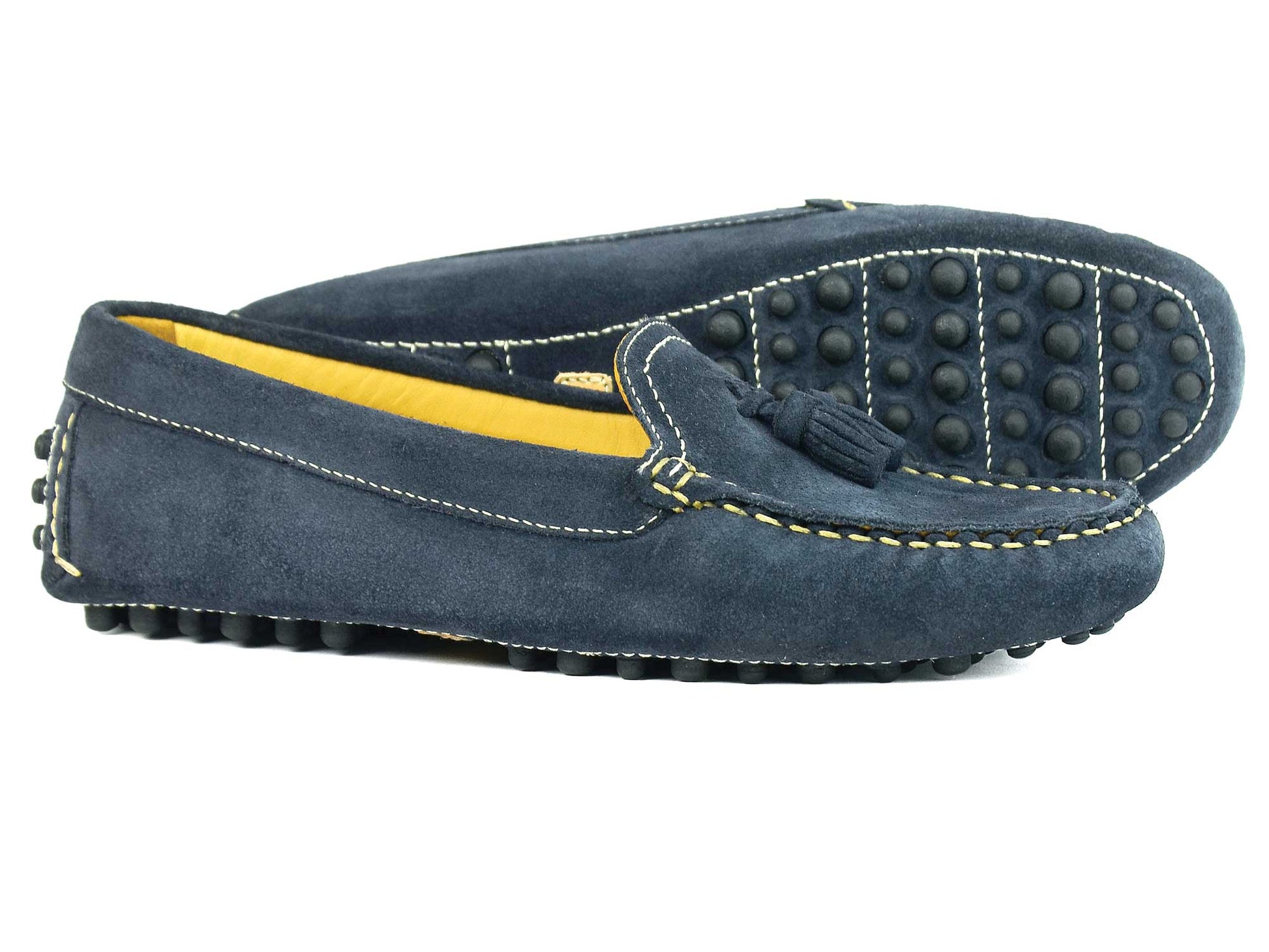 The SALE SALCOMBE Ladies Navy Suede Driving Loafer with Tassels by Orca Bay - dark blue suede loafers with tassels and yellow interiors, feature a non-slip rubber sole and white stitching, artfully arranged one in front of the other.