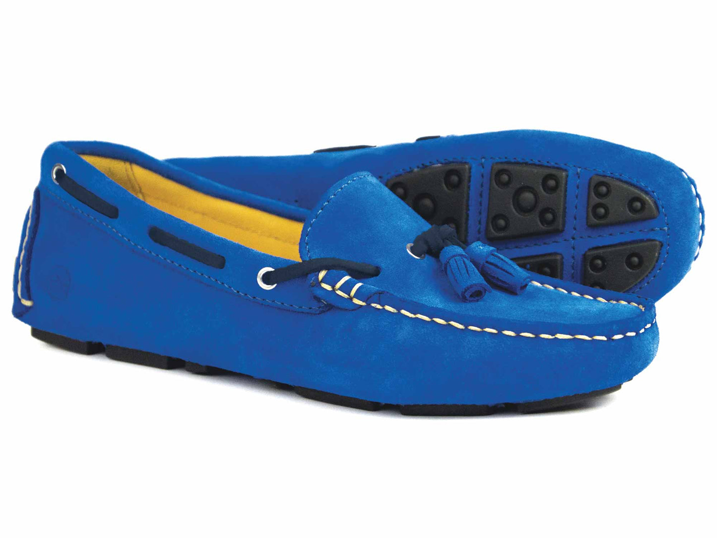 The Orca Bay Sicily Royal Blue Suede Ladies Tassel Loafers feature royal blue suede with tassels, white stitching, and rubber sole segments. They include a yellow interior lining and black accents around the opening and sides.