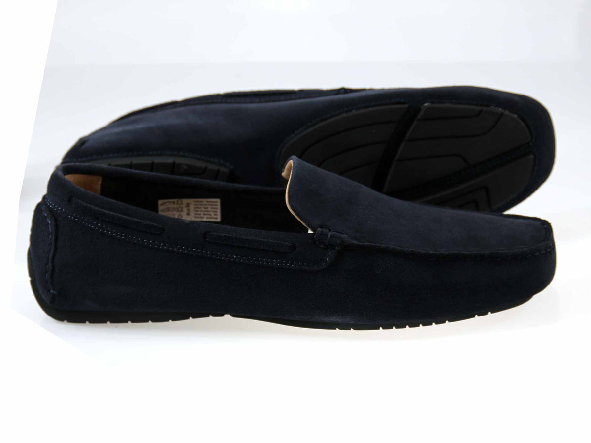 The Orca Bay Silverstone Navy Suede Driving Shoes are featured here, with one men’s loafer positioned flat and the other on its side to showcase the non-slip rubber sole’s tread pattern—highlighting how this classic style from Orca Bay is both stylish and practical.