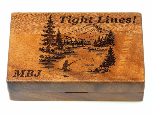 Introducing the Cathcart Elliot Personalised Pocket Sized Walnut Fishing Fly Box (14x9cm, opens flat), custom engraved with a detailed scene of a fisherman by a river, surrounded by trees and a mountain. The lid features the words “Tight Lines!” alongside the initials “MBJ,” making this elegant walnut fly box a truly personal and thoughtful gift for any angler.