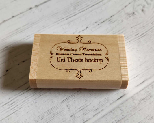 The Cathcart Elliot Personalised Maple wood USB 3.0 16GB flash drive rests elegantly on a white surface, engraved with options like Wedding Memories and features decorative swirls. It merges function and style, ideal for use as a keepsake or in a presentation box.