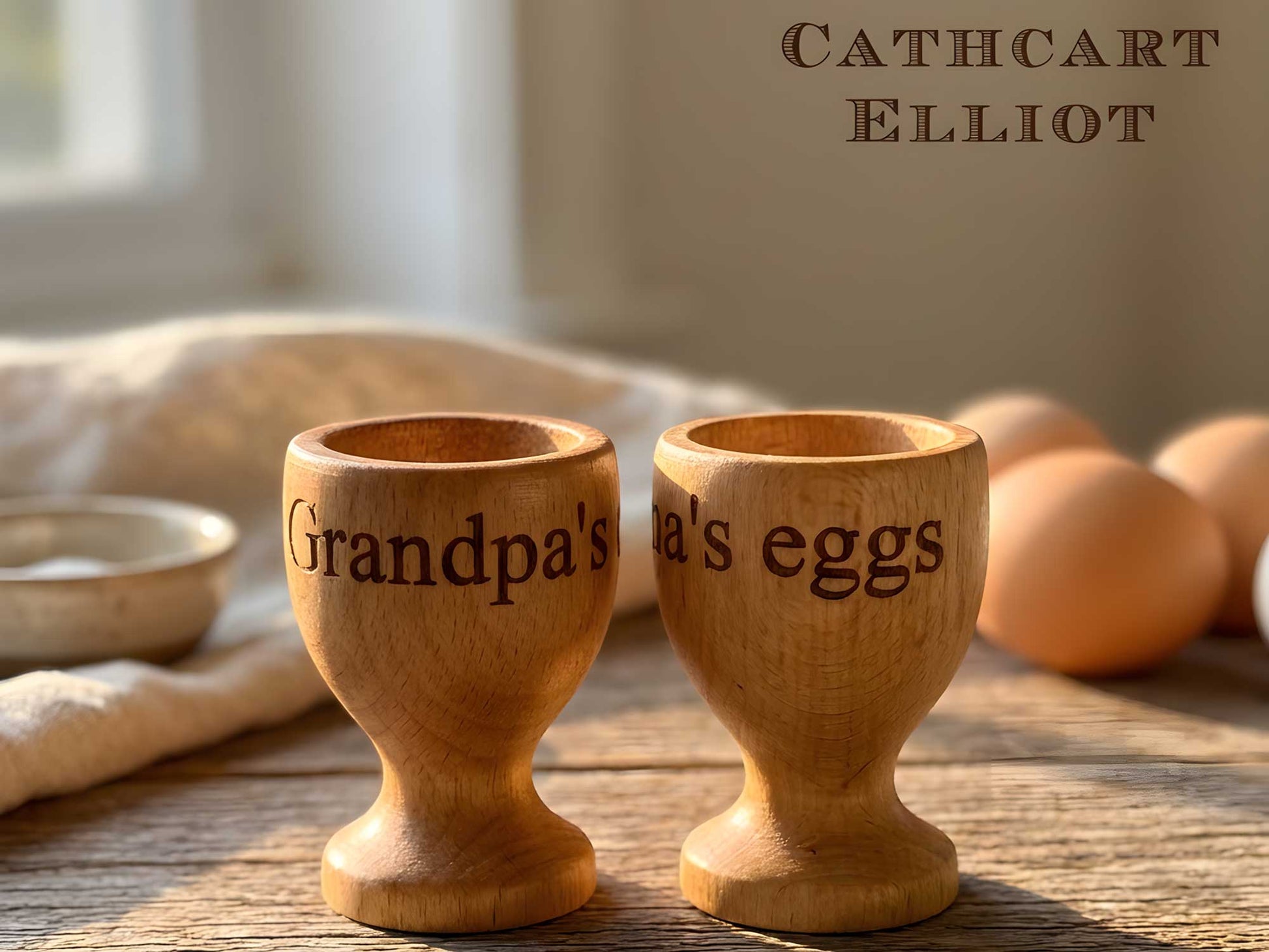 Two Personalised Wooden Egg Cups by Cathcart Elliot sit on a table, one engraved "Grandpas," the other partially reading "eggs." Brown eggs and a white dish are in the background.