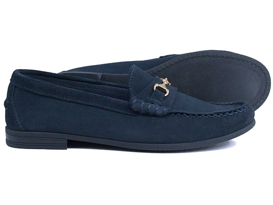 The Orca Bay Zurich Ladies Navy Suede Buckle Loafer features black soles, a decorative metal bit, and visible front stitching. One lightweight Orca Bay loafer stands upright while the other rests on its side.